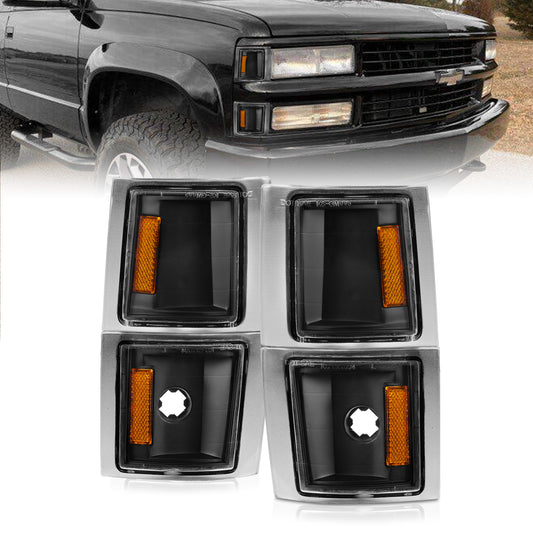 Car fog light covers with orange reflectors in front of a black truck.